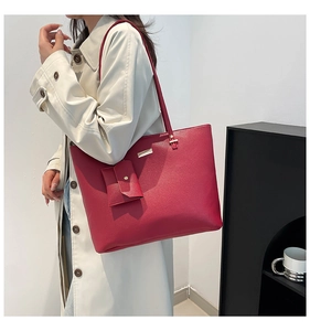 Macro detail of red lychee grain leather tote bag with gold metal buckle and coin purse