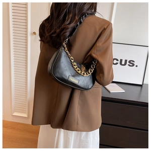 Detail of black crescent shoulder bag with chunky gold chain and fashion label on front