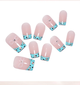 Détail de faux ongles French léopard avec pointes bleues et nœuds en strass