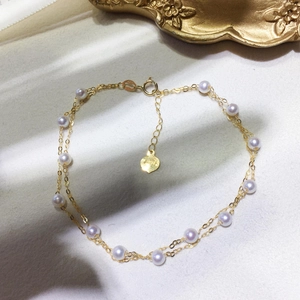 Detail of 18k gold double-layer chain bracelet with natural white pearls and heart charm