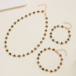 Detailed close-up of golden beaded jewelry set with black heart charms and lobster clasps