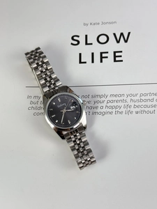 Macro view of silver steel watch with grey sunray dial and date window display