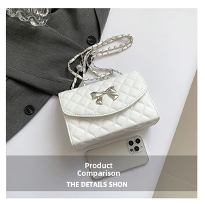 Close-up of white quilted handbag featuring a silver metal bow and chain strap detail