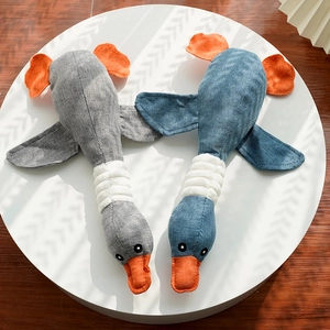 Detailed view of grey and blue plush duck chew toys on a circular white display stand