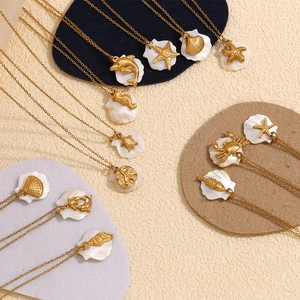 Flat lay of gold starfish and sea turtle pendants on colorful pads with shell inlays