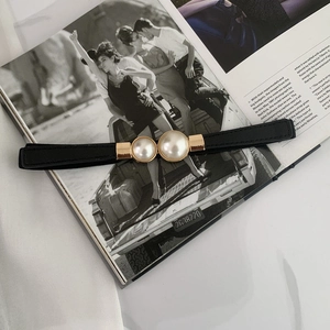 Detail of elegant gold buckle with white pearls on a black elastic waist belt