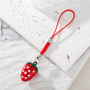 3D strawberry bell pendant with red braided lanyard on white textured stone background