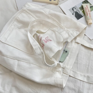 Top view of white canvas tote bag interior with pink embroidery and phone for scale