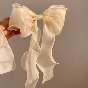 Detailed view of an oversized cream ribbon bow hair clip with translucent organza fabric