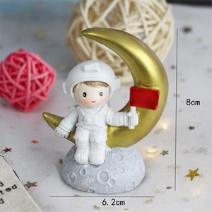 Astronaut sitting on golden moon cake topper with size dimensions 8cm by 6.2cm