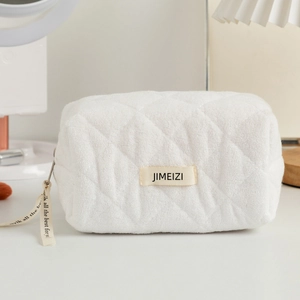Quilted white cotton cosmetic bag with chic ribbon handle and boxy storage design