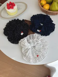 Close-up of three polka dot scrunchies with handmade labels and red heart buttons