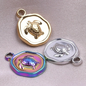 Dettaglio ravvicinato di tre ciondoli tartaruga in oro, argento e tonalità arcobaleno