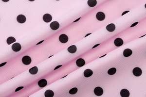 Close-up of pink fabric with black polka dot print showing texture and soft drapes