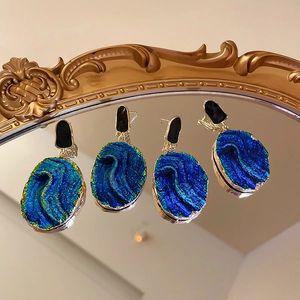 Close-up of vintage resin drop earrings with blue agate texture and golden irregular edges