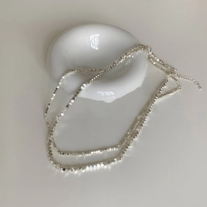 Détail de perles polyèdres argentées irrégulières sur un collier avec chaîne réglable