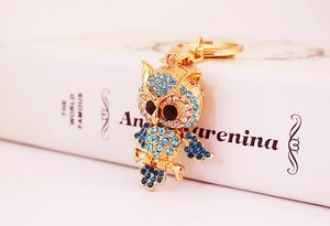 Close-up of golden owl keychain with sparkling blue and clear rhinestones on book