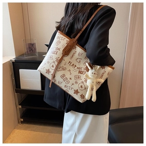 Detail of white graffiti tote bag with plush bunny charm and brown leather straps