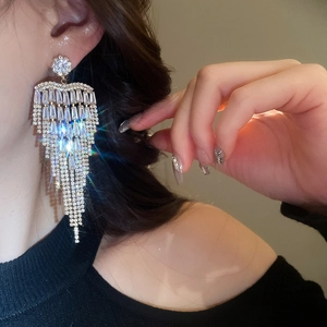 Close-up of sparkling long flower tassel earrings with zircons worn on model