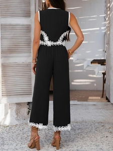 Détail de la combinaison noire sans manches avec broderie en dentelle blanche à la taille