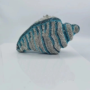 Detailed close-up of shell-shaped clutch bag with blue and silver rhinestone stripes