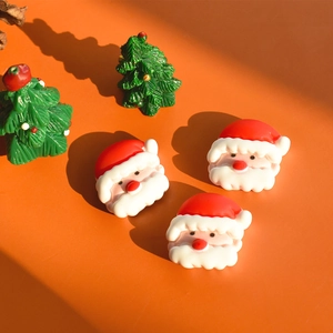 Detailed view of resin Santa Claus and Christmas tree charms on warm orange background