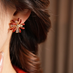 Close-up of red enamel flower earrings with white zircon on a model's ear