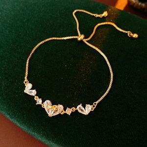 Detail of 18K gold plated heart bracelet with zircon stones on green velvet