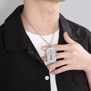 Close-up of men's square pendant necklace with intricate cutout cross and woven chain
