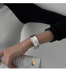 Chic irregular wide silver cuff bracelet styled on model with minimalist high-end look