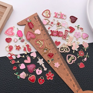 Flat lay of pink and red alloy heart charms with wooden ruler showing various sizes