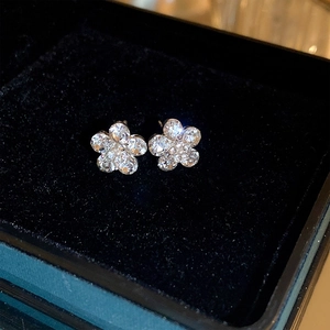 Macro shot of silver flower earrings with sparkling rhinestones on black velvet