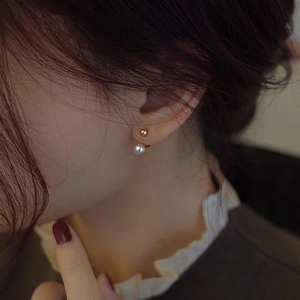 Minimalist gold ball and freshwater pearl earrings on a model for a vintage look
