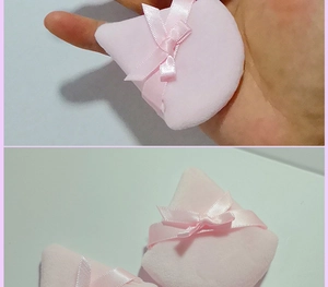 Close-up of pink triangular velvet makeup puffs with ribbon bows for powder