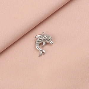 Macro shot of silver dolphin pendant with textured finish on soft pink fabric