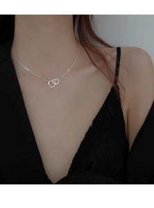 Detail of silver interlocking hearts necklace worn by a model with a black lace outfit