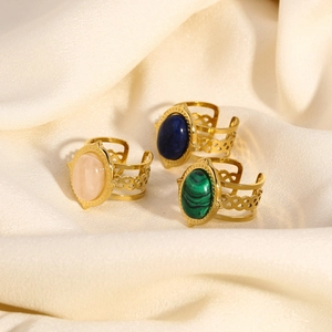 Oval gemstone stainless steel rings in three colors on elegant silk background