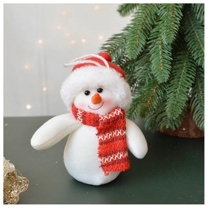 Close-up of plush Christmas snowman ornament with red hat and scarf on tree background