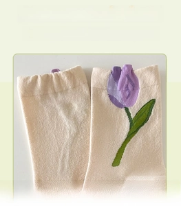 Detail view of cream knit socks with 3D purple tulip petals and floral patterns
