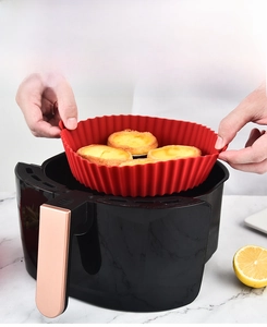 Detail of red silicone air fryer liner with side handles and wave edge containing egg tarts