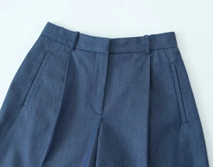 Close-up of deep blue denim trousers showing waist belt loops and fabric texture