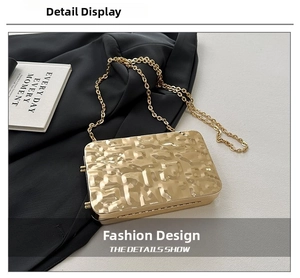 Detail of a gold evening clutch featuring a hammered metal texture and gold chain strap