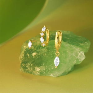 Detail of three-piece gold stud earring set with marquise stones on a green crystal