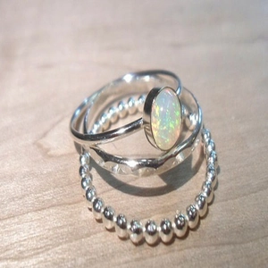 Three-piece silver ring set featuring an opal center stone and hammered texture detail