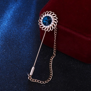 Macro shot of rose gold sunburst brooch with navy blue crystal and tassel chain
