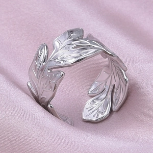 Detailed view of leaf-shaped silver stainless steel ring on elegant pink silk fabric
