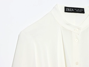 Detail of white long-sleeve blouse collar and shoulder with delicate silk texture