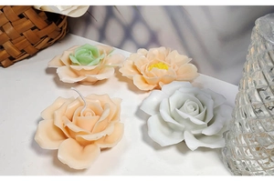 Close-up of DIY rose shape aroma candles in pink, beige, and white on a desktop