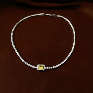Close-up of emerald cut yellow crystal tennis necklace with silver halo setting
