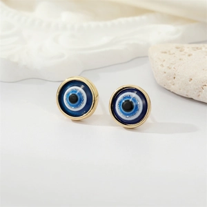 Detail of round devil's eye stud earrings with blue resin and golden metal borders